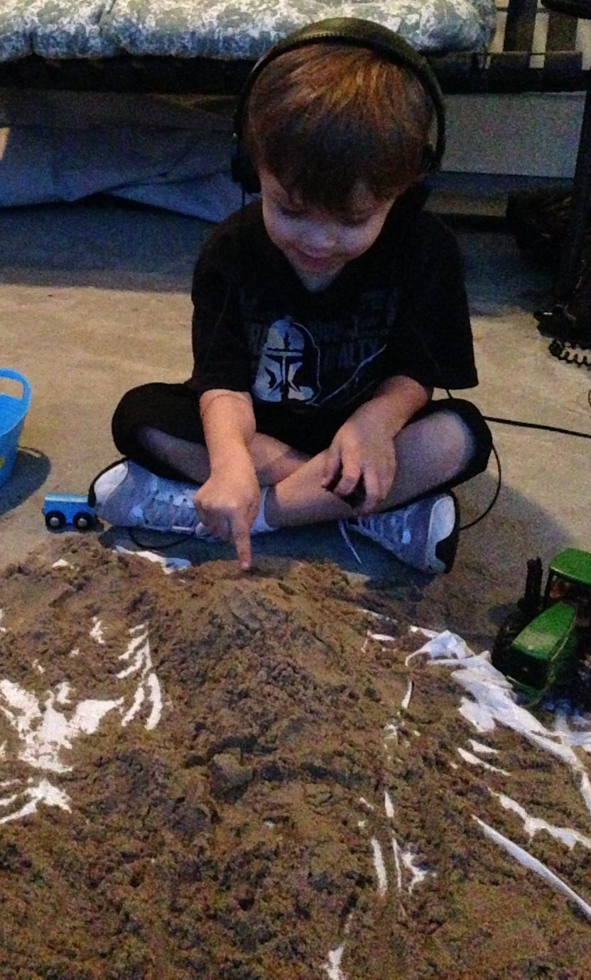 boy playing in sand while wearing headphones