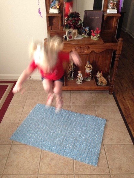 little girl jumping on bubble wrap to stimulate the eustachian tubes