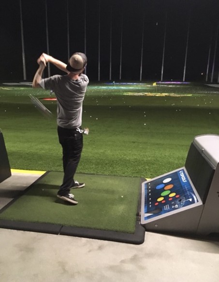 man swinging a golf club at a top golf range