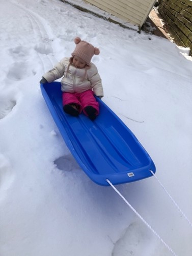 little girl in a sled outside in the snow