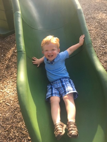 A little boy going down the slide