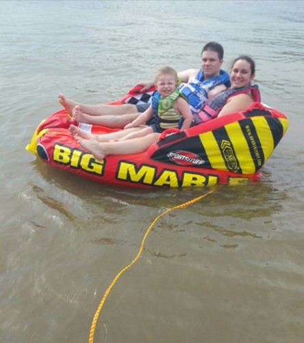 Two parents and son in a water tube on the lake