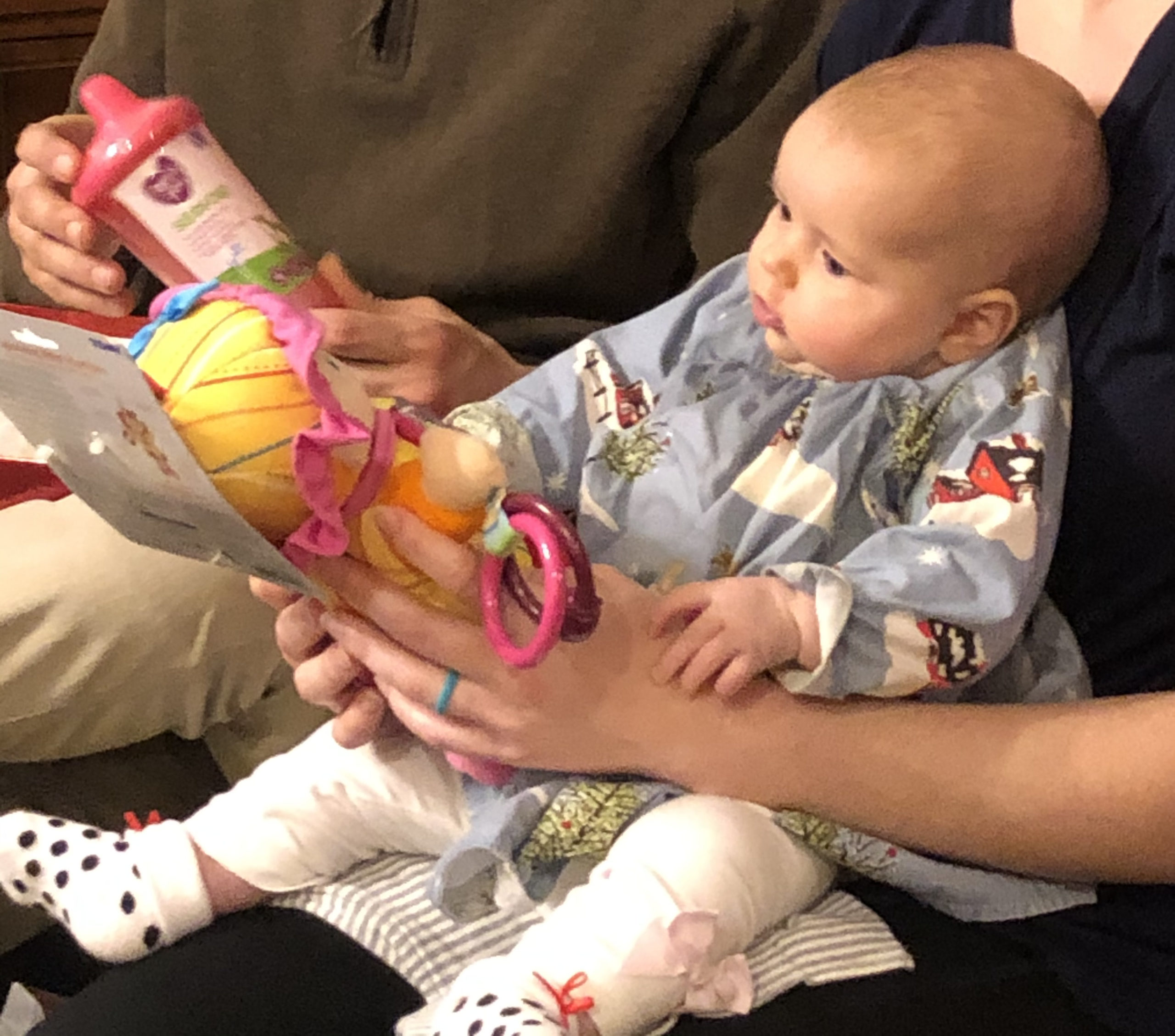 infant looking at the face of a stuffed doll with a yellow hat, outfit, and pink ribbon around the hat.